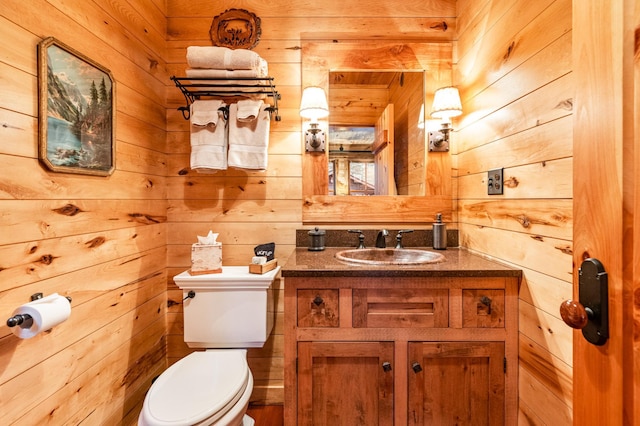 bathroom featuring wood walls, toilet, and vanity