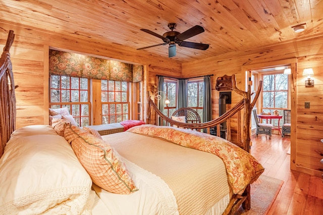bedroom featuring wooden walls, wood ceiling, multiple windows, and hardwood / wood-style floors