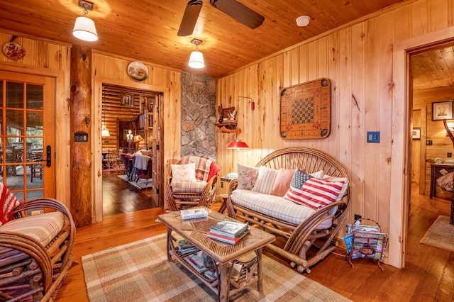 living room featuring wooden walls, a ceiling fan, wood-type flooring, and wood ceiling