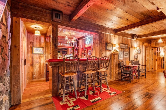 indoor dry bar with wooden walls, wood-type flooring, beamed ceiling, and wooden ceiling