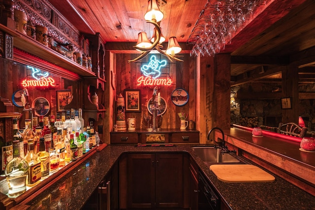 indoor wet bar with black dishwasher, a chandelier, and wooden ceiling