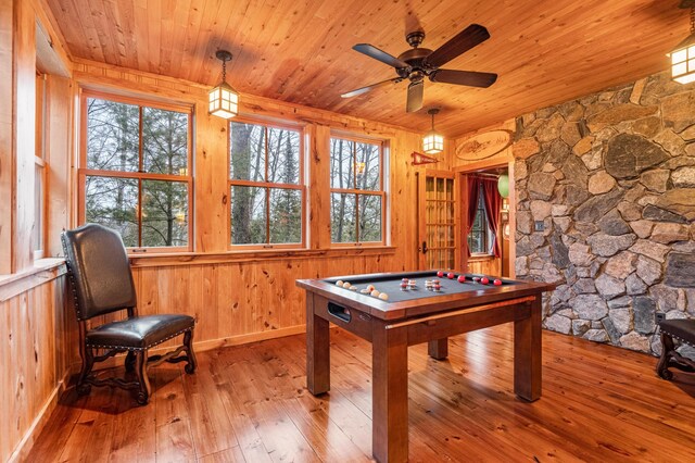 recreation room with hardwood / wood-style flooring, plenty of natural light, wood ceiling, ceiling fan, and wood walls