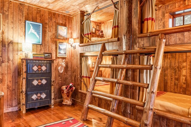 stairs featuring wooden walls, wood ceiling, and hardwood / wood-style floors