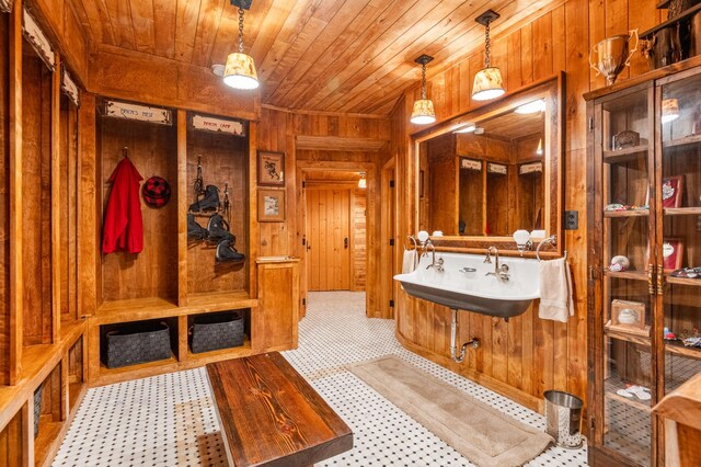 bathroom with wooden walls, wooden ceiling, and a sink
