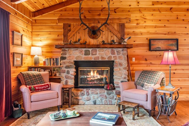 living area featuring wood finished floors, a stone fireplace, wooden walls, and wood ceiling