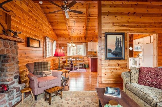living area featuring vaulted ceiling, wooden walls, light wood-style flooring, a ceiling fan, and wooden ceiling