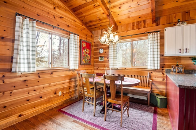 dining area with vaulted ceiling, healthy amount of natural light, wood walls, wood ceiling, and a chandelier