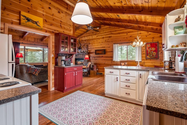 kitchen with freestanding refrigerator, a sink, wooden walls, light wood finished floors, and wood ceiling