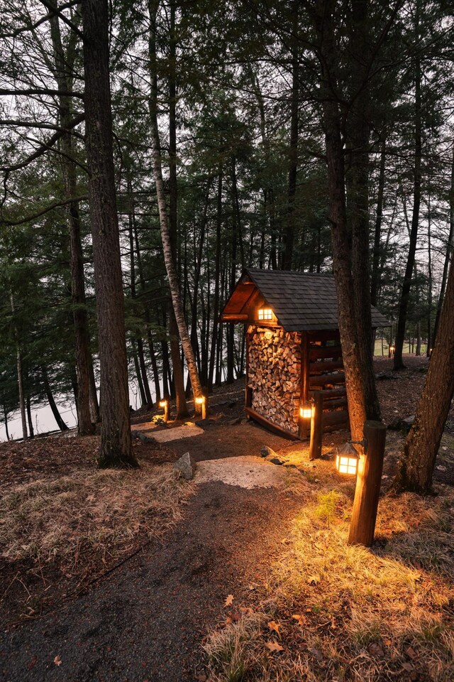view of front of house with stone siding, roof with shingles, and an outdoor structure