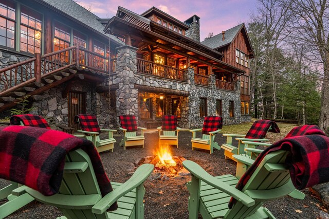 patio terrace at dusk with an outdoor fire pit and a balcony