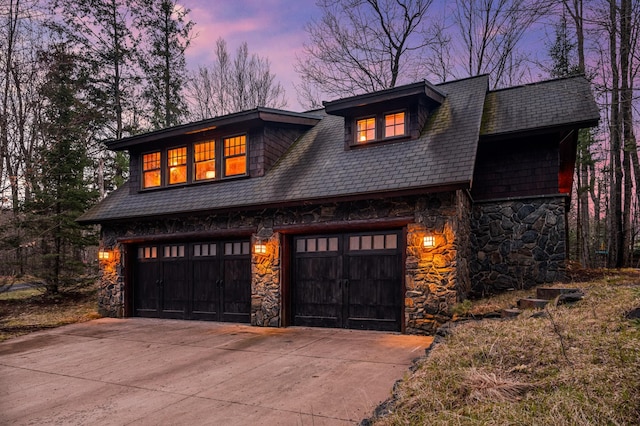 view of front facade featuring stone siding, concrete driveway, and a garage