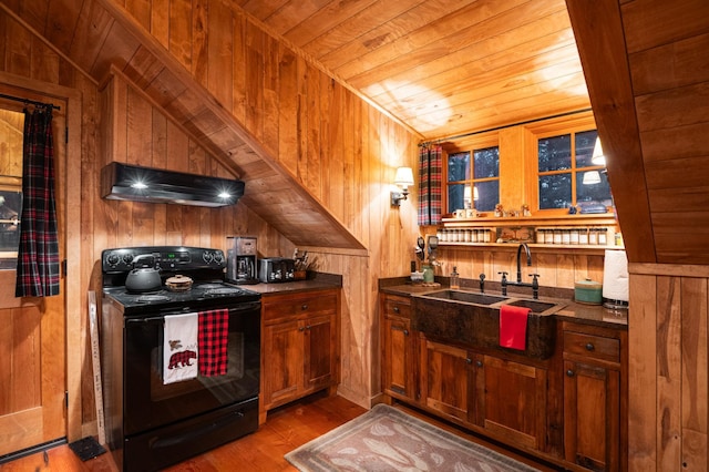 kitchen with electric range, under cabinet range hood, wood ceiling, wood walls, and a sink