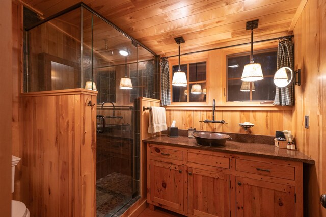 bathroom featuring a shower stall, vanity, wooden walls, wood ceiling, and toilet