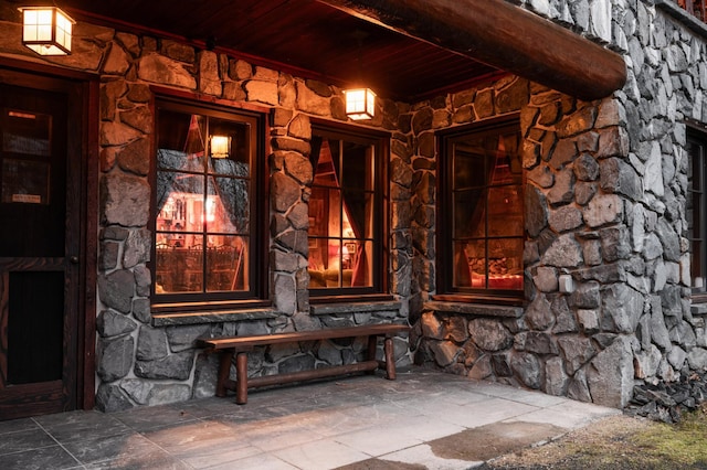 view of exterior entry featuring stone siding and a porch