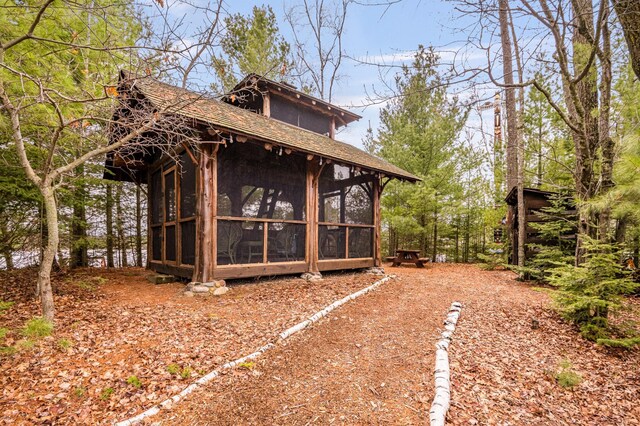 view of side of property featuring a sunroom and a shingled roof