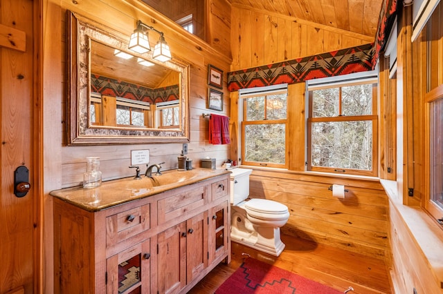 bathroom with wooden walls, wood finished floors, vanity, wooden ceiling, and lofted ceiling