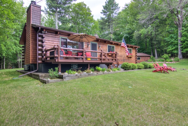 rear view of property featuring a chimney, a yard, a deck, and log siding