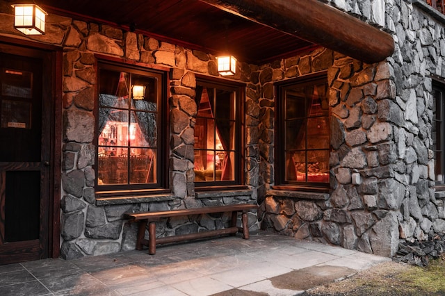 doorway to property with stone siding and a porch