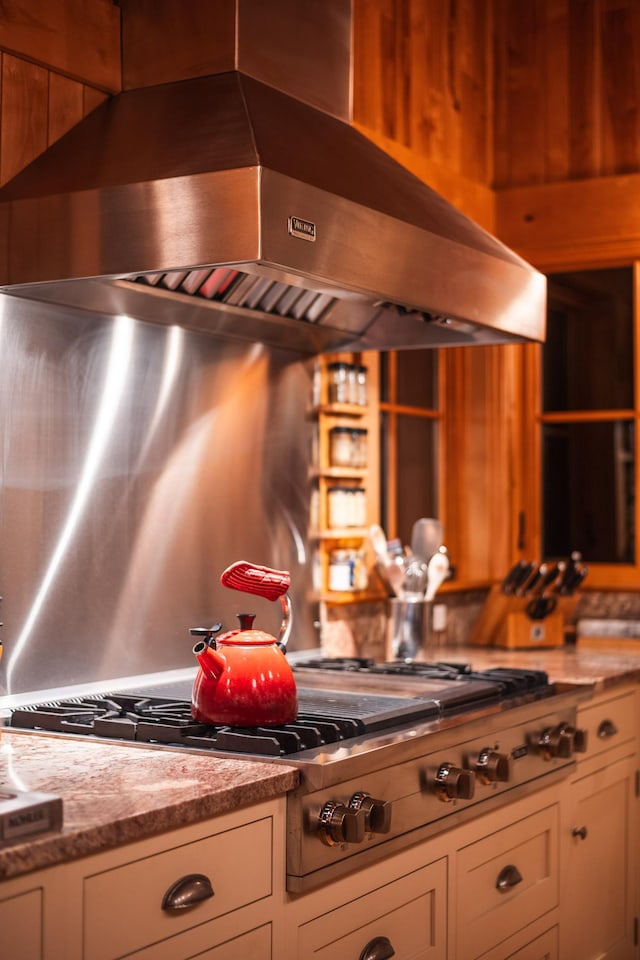 kitchen featuring exhaust hood, stainless steel gas stovetop, white cabinets, and light stone counters