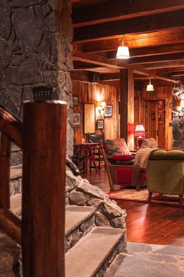 living area featuring wood walls, hardwood / wood-style flooring, and beam ceiling