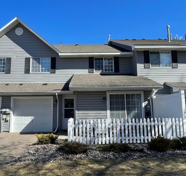 view of front of home with aphalt driveway, an attached garage, fence, and a shingled roof