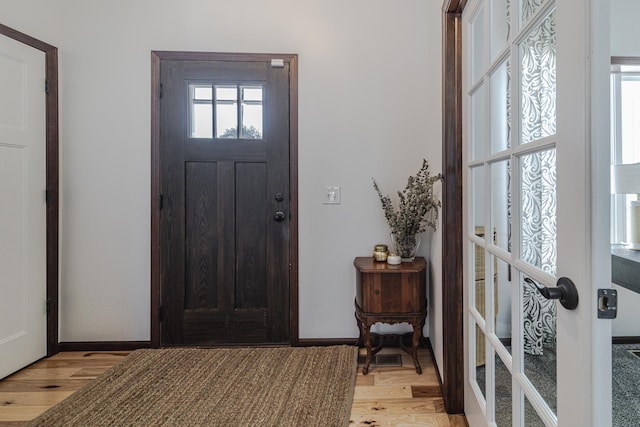 foyer featuring a healthy amount of sunlight, light wood-style flooring, baseboards, and french doors