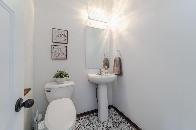 half bathroom featuring toilet and baseboards