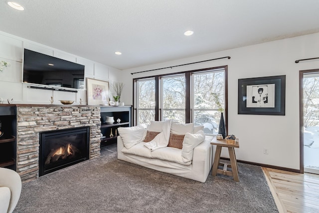 living room featuring a fireplace, recessed lighting, a textured ceiling, wood finished floors, and baseboards