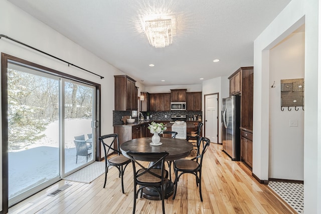 dining space featuring a chandelier, light wood finished floors, recessed lighting, and baseboards