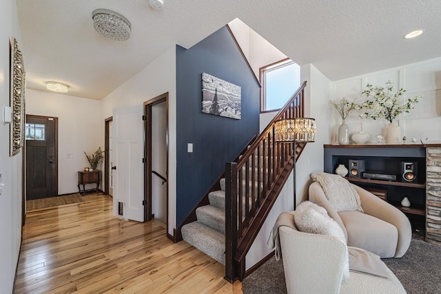 stairs featuring a textured ceiling, vaulted ceiling, and wood finished floors