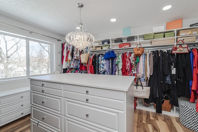 spacious closet with a chandelier and wood finished floors