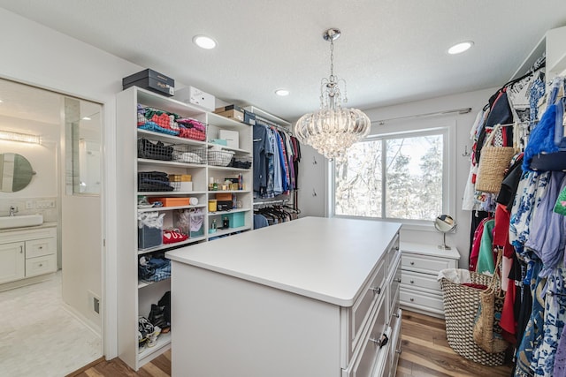 spacious closet with an inviting chandelier, a sink, visible vents, and light wood-style floors