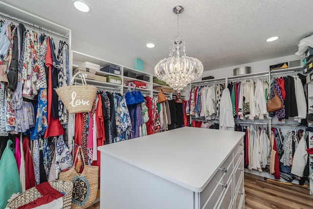 spacious closet with a chandelier and wood finished floors