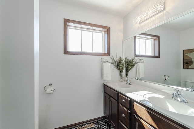 bathroom with toilet, a sink, baseboards, and double vanity