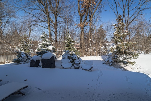 yard layered in snow featuring a garage and fence