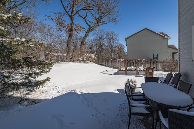 snowy yard with outdoor dining space and a deck