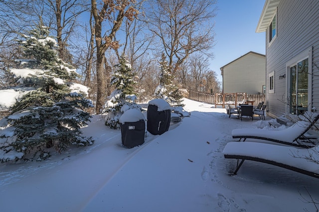 snowy yard featuring outdoor dining area and fence