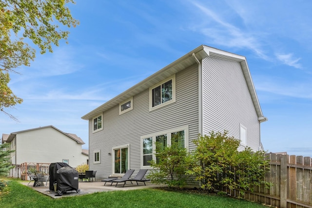 rear view of property with fence, a lawn, and a patio