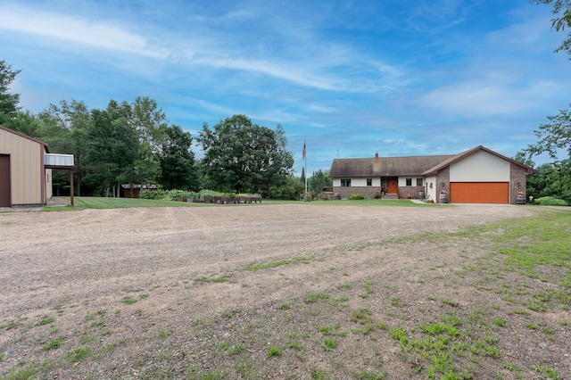 view of yard featuring a garage and dirt driveway