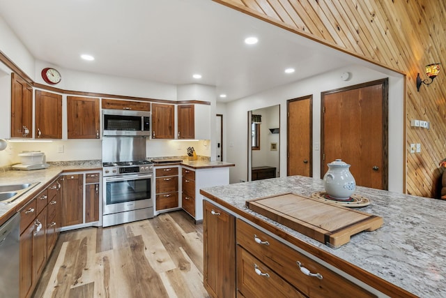 kitchen featuring brown cabinets, stainless steel appliances, recessed lighting, light countertops, and light wood-style flooring