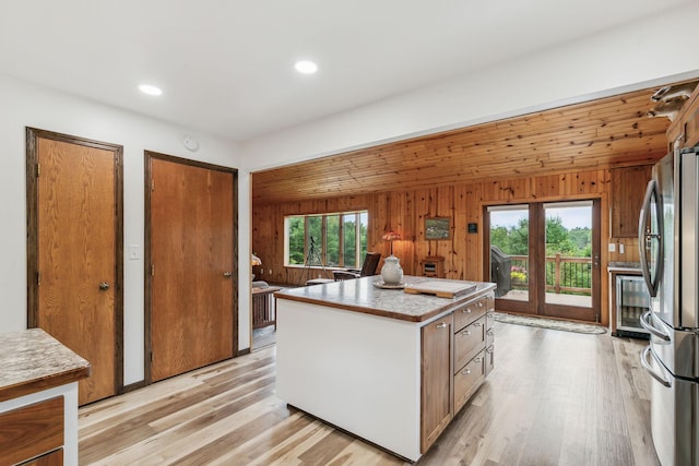 kitchen with light wood-style floors, freestanding refrigerator, a center island, and a healthy amount of sunlight