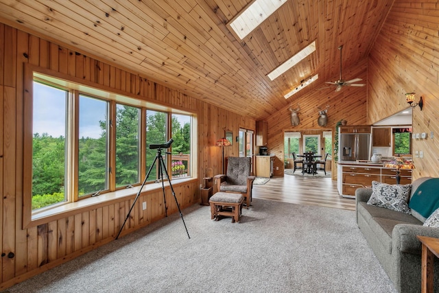 living area featuring high vaulted ceiling, wood walls, a skylight, and wood ceiling