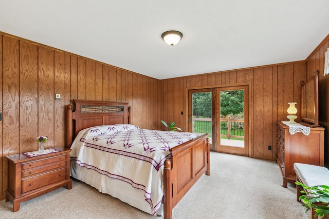 bedroom with light carpet, wood walls, and access to exterior