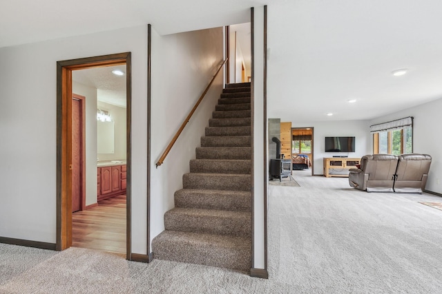 stairs with carpet floors, a wood stove, baseboards, and recessed lighting