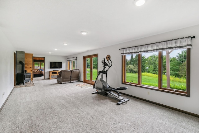 exercise room featuring recessed lighting, carpet, a wood stove, and baseboards