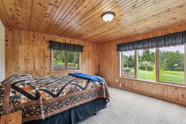 carpeted bedroom with wood ceiling, multiple windows, and wooden walls