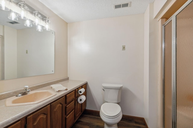 bathroom featuring a textured ceiling, toilet, wood finished floors, and visible vents