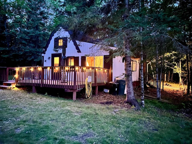 rear view of house featuring a lawn and a deck