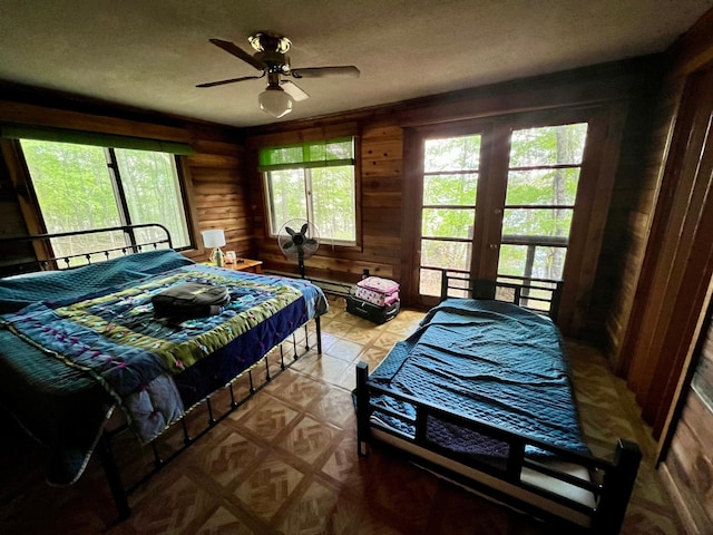 bedroom featuring wooden walls, a textured ceiling, and ceiling fan