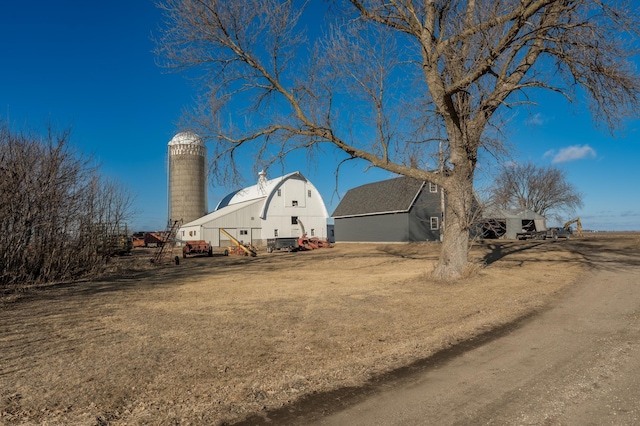 exterior space featuring a gambrel roof, an outdoor structure, a chimney, and a barn